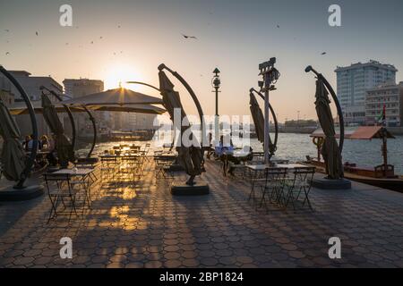 Vista del Creekside cafe e delle barche sul Dubai Creek al tramonto, Bur Dubai, Dubai, Emirati Arabi Uniti, Medio Oriente Foto Stock