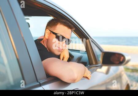 Bell'uomo che guida la sua auto sullo sfondo del mare. Foto Stock