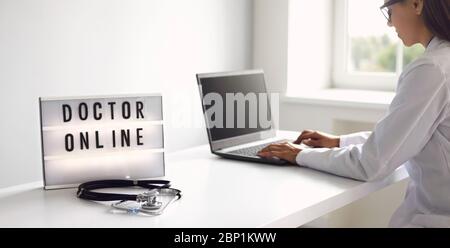 Medico online. Online medico digitando diagnosi messaggio analizza prescrizione utilizzando il notebook gadget webcam video conferenza in clinica ufficio. Foto Stock