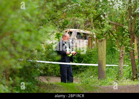 Una scena di ufficiale di crimine protegge un veicolo bruciato a Swillington, dove il conducente del veicolo schiantato fuggì dalla scena. Foto Stock