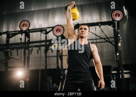 Giovane muscoloso con perfetto corpo bello che indossa sportswear che solleva pesi pesanti liberi Foto Stock