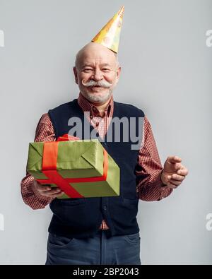 L'uomo anziano felice nel cappello del partito contiene la scatola del regalo Foto Stock