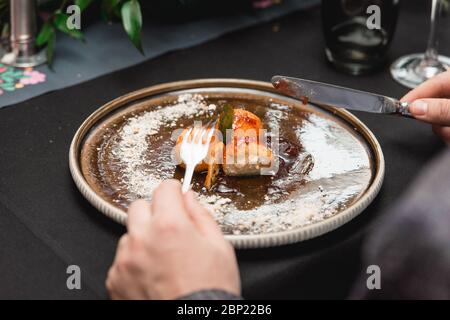 Uomo in un ristorante che mangia polpette di formaggio caserario fatte a mano, dolce ungherese servito con marmellata di fragole sudorate Foto Stock