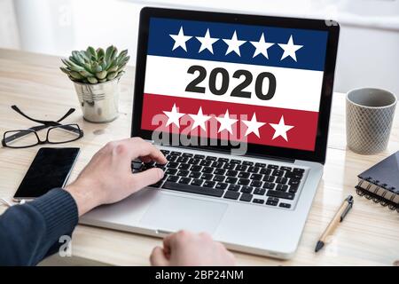 Elezioni online, votazione digitale sulle elezioni americane del 2020. Uomo che lavora con un computer portatile, 2020 su schermo, sfondo ufficio. Foto Stock