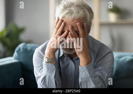 Nonno pensionato infelice di mezza età che soffre di alta pressione sanguigna. Foto Stock