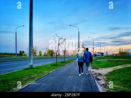 Una giovane coppia cammina per strada la sera. La vista da dietro. Foto mobile. Foto Stock
