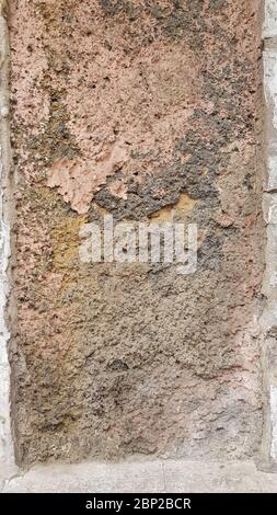 Rivestimento della parete intemperie con superficie di pietra marrone ruvida danneggiata. Grunge muro di costruzione ha bisogno di riparazioni. Sfondo di costruzione con spazio di copia Foto Stock