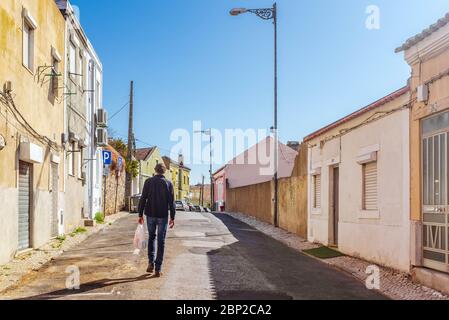 Uomo con borsa in plastica che cammina lungo la strada a Lisbona. Foto Stock