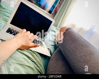 La ragazza si riposa a casa davanti al computer. Un primo piano. Foto mobile. Foto Stock