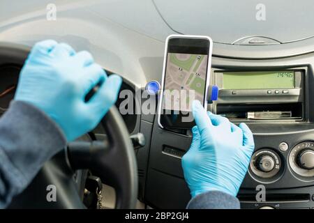 Mani gugorate del contemporaneo tassista touchscreen dello smartphone mentre si utilizza l'applicazione navigatore per trovare l'indirizzo del cliente Foto Stock