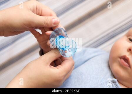 Le mani della madre che danno un capezzolo al suo figliolo Foto Stock