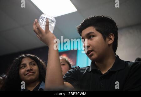 L'astronauta Ricky Arnold al Challenger Centre UNO studente tiene un bicchiere d'acqua con una scheda Alka-Seltzer mentre conduce un esperimento sull'effervescenza, venerdì 3 maggio 2019, presso il Challenger Centre di Lanham, MD. L'astronauta della NASA Ricky Arnold li ha aiutati a realizzare l'esperimento che ha condotto anche durante la sua missione di 197 giorni a bordo della Stazione spaziale Internazionale (ISS) durante le Expeditions 55/56. Foto Stock