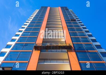 Ascensore sospeso con vista dall'alto in un alto edificio residenziale in costruzione, decorazione della facciata e delle finestre Foto Stock