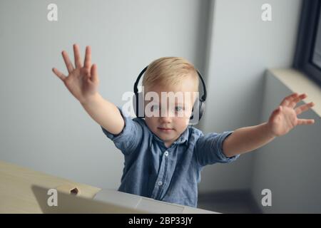 Un bambino gioca su un computer portatile e ascolta la musica Foto Stock