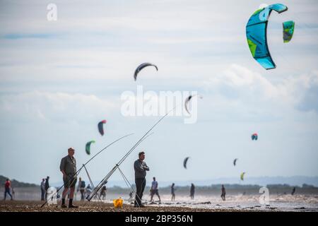 Pescatori sulla spiaggia di Weston-super-Mare con kite surfers in background come le restrizioni Coronavirus sono attenuati in Inghilterra. Foto Stock