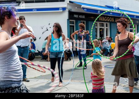 Gli hula hoops giocano per le strade durante il Brighton Festival 2012 a Brighton, Regno Unito Foto Stock