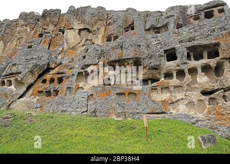 Cripte tagliate nella scogliera di fronte Otuzco sito archeologico, vicino Cajamarca, Perù marzo Foto Stock