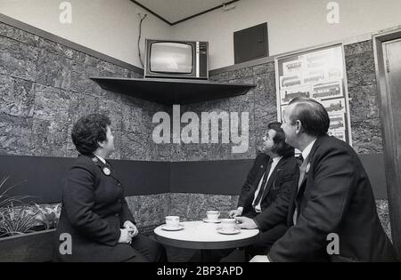 Interno, stanza di riposo del personale dell'autobus New Cross, Londra del sud, Inghilterra, 1974, l'immagine mostra tre membri dell'equipaggio in uniforme che hanno una pausa e una tazza di tè e che guardano una piccola televisione portatile. Foto Stock