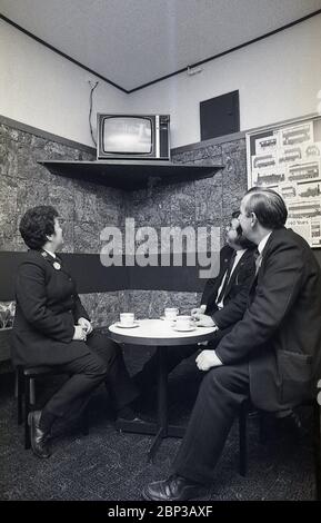 Interno, Bus staff Rest room New Cross, South London, England, 1974, immagine mostra tre equipaggi in uniforme che hanno una pausa e una tazza di tè e guardando una piccola televisione portatile. Foto Stock