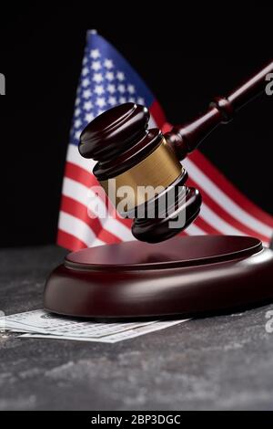 Gavel di legno, soldi sullo sfondo della bandiera americana su sfondo nero in studio Foto Stock