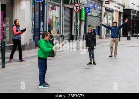 La famiglia gioca a fare un'esultante sulla deserta Grafton Street nel centro di Dublino, mentre le aziende e i negozi rimangono chiusi e i calci piovono a causa del Covid-19. Foto Stock