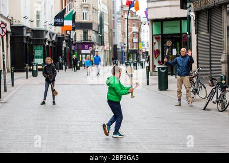 La famiglia gioca a fare un'esultante sulla deserta Grafton Street nel centro di Dublino, mentre le aziende e i negozi rimangono chiusi e i calci piovono a causa del Covid-19. Foto Stock