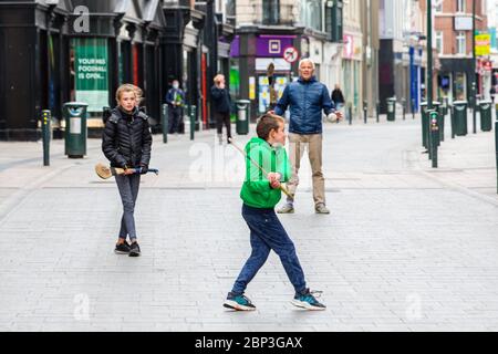 La famiglia gioca a fare un'esultante sulla deserta Grafton Street nel centro di Dublino, mentre le aziende e i negozi rimangono chiusi e i calci piovono a causa del Covid-19. Foto Stock