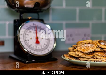 Torte gallesi fatte in casa (Bakestones) isolate su piatto verde con pesate in background arrossate Foto Stock