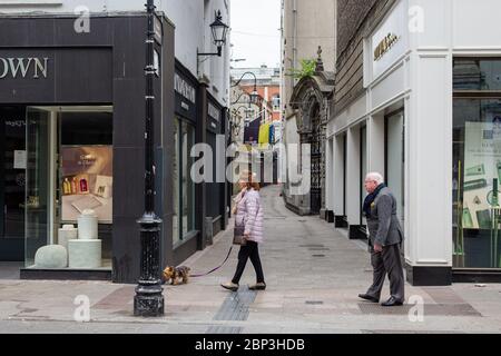 Coppia senior che cammina attraverso una tranquilla Grafton Street nel centro di Dublino, mentre la caduta dei piedi precipita a causa della pandemia del coronavirus. Civid-19 in Irlanda. Foto Stock
