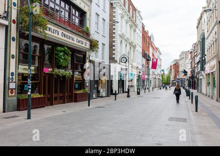I pedoni passeggiano attraverso una strada deserta Grafton nel centro di Dublino, mentre i negozi rimangono chiusi a causa di restrizioni pandemiche di coronavirus. Foto Stock