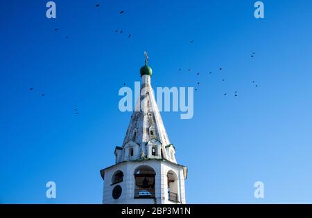 Uccelli cerchiare il campanile della chiesa ortodossa ascensione a Suzdal in inverno. Foto Stock