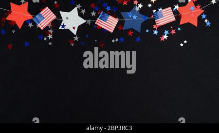 4 luglio decorazione giorno dell'Indipendenza su sfondo scuro. Confetti bianchi blu rosso, stelle nei colori nazionali degli Stati Uniti e bandiere americane. Foto Stock