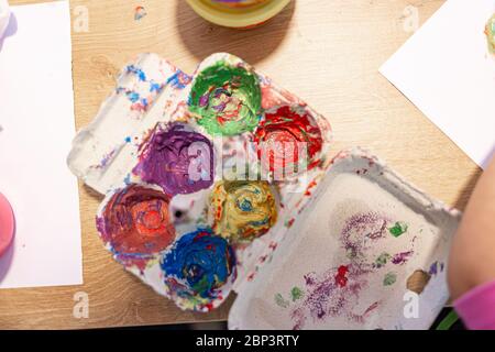 Tavolozza dei colori che mescola i colori su un ovulo su una scena domestica con il bambino che gioca Foto Stock