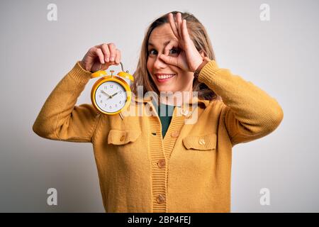 Giovane bella donna bionda che tiene sveglia in piedi su sfondo bianco isolato con faccia felice sorridente che fa segno ok con mano su lookin occhio Foto Stock