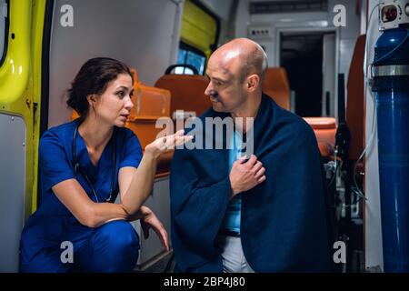 Una lavoratrice medica femminile che parla con un uomo da cui è stato salvato il fuoco Foto Stock