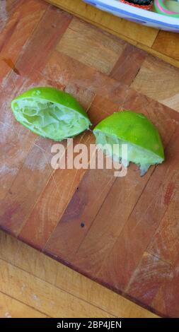 Lime centrifugate tagliate a metà su un tagliere di legno; spremute o spremute per la spremitura. Foto Stock