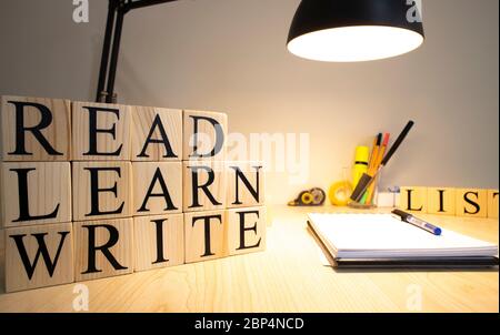 Su cubi di legno, leggere imparare a scrivere, scrivere testi. Sono presenti lampada da tavolo e blocco note. Foto Stock