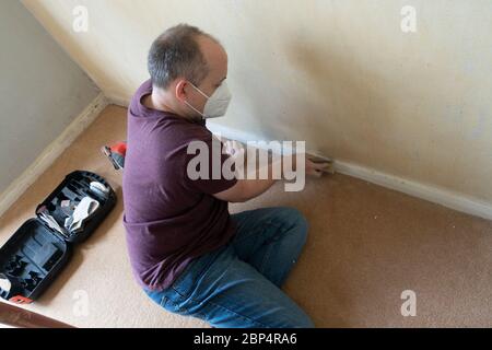 Un uomo di mezza età levigare bordo di bordo prima di verniciarlo come aprt di un progetto DIY. Foto Stock