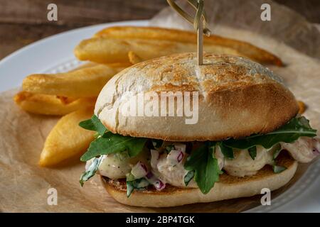 Insalata di gamberi su involtino di hoagie con rucola e patate fritte in forno in casa. Foto Stock