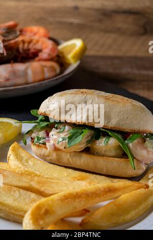 Insalata di gamberi su involtino di hoagie con rucola e patate fritte in forno in casa. Foto Stock