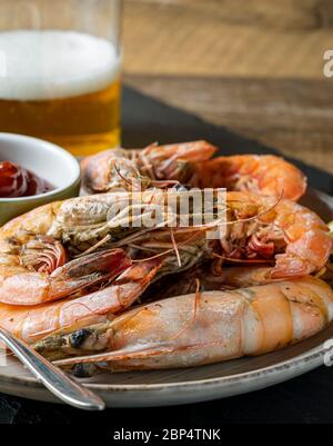 Antipasto di gamberi al vapore su vassoio di ardesia e un bicchiere di birra sullo sfondo. Foto Stock