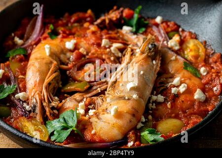 Gamberi cotti in teglia di ghisa con salsa di pomodoro rosso con prezzemolo e formaggio feta. Foto Stock