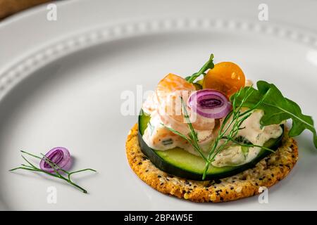 Insalata di gamberetti su cracker di grani interi. Piatto di servizio bianco come sfondo. Foto Stock