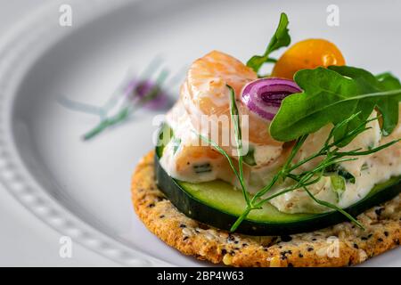 Insalata di gamberetti su cracker di grani interi. Piatto di servizio bianco come sfondo. Foto Stock