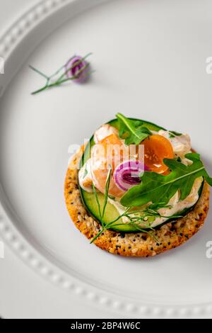 Insalata di gamberetti su cracker di grani interi. Piatto di servizio bianco come sfondo. Foto Stock