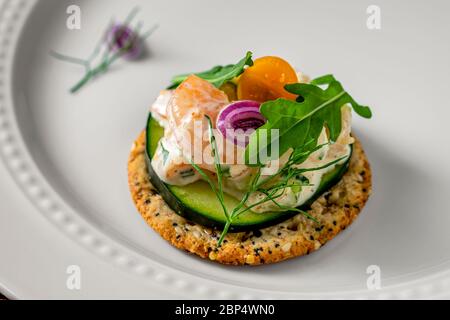 Insalata di gamberetti su cracker di grani interi. Piatto di servizio bianco come sfondo. Foto Stock