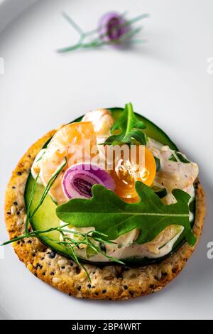 Insalata di gamberetti su cracker di grani interi. Piatto di servizio bianco come sfondo. Foto Stock