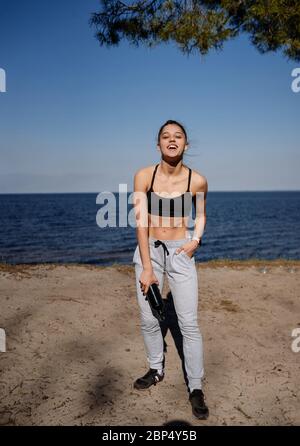 Fitness giovane donna cammina nel parco e posa per la macchina fotografica Foto Stock