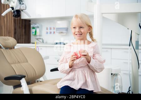 Una bambina che ascolta un medico che le spiega le sue cose sui denti e su come prenderli cura di loro Foto Stock