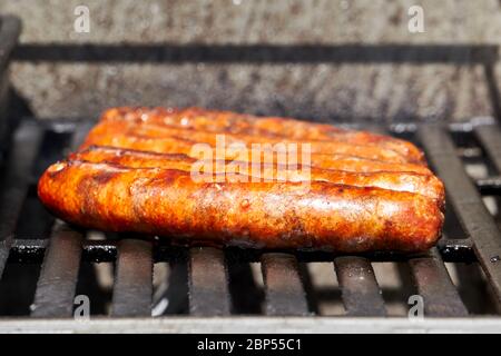 Salsicce merguez grigliate su un barbecue a gas durante UNA bella giornata estiva Foto Stock